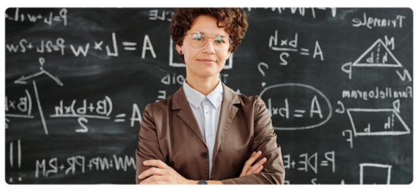 A physics graduate stands in front of a blackboard full of equations